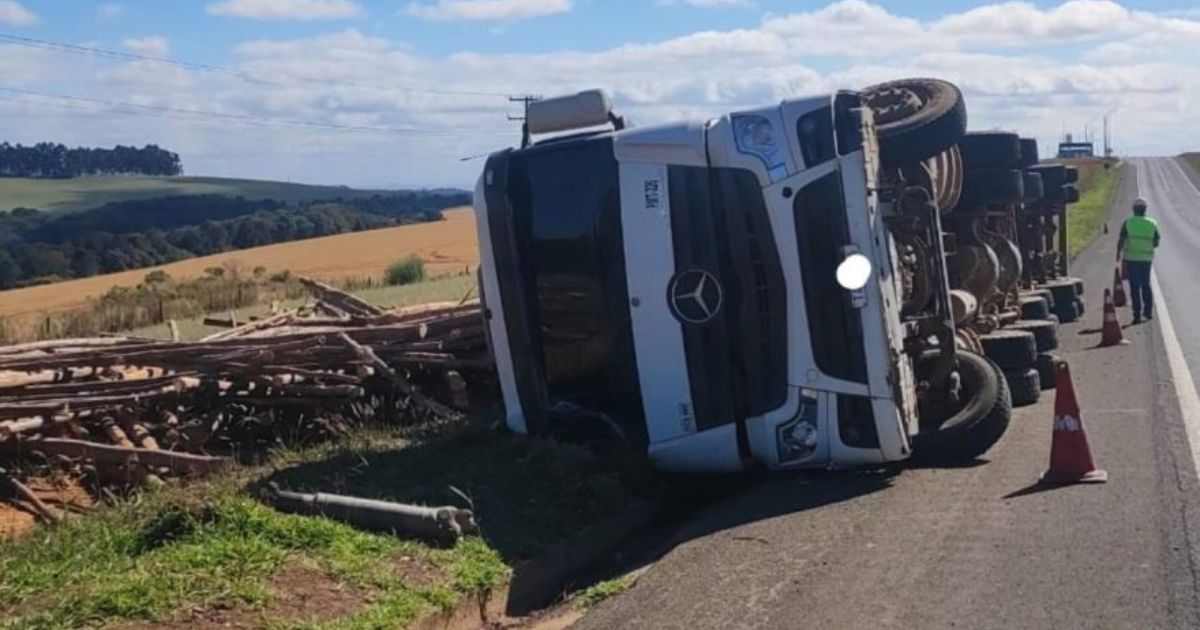 Caminhão carregado com toras de madeira tomba na PR-151